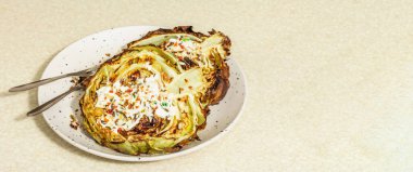 Ev yapımı vejetaryen lahana bifteği, baharat ve sos. Sağlıklı yiyecekler servis tabağında yemeye hazır, çatal bıçak takımı. Taş beton arkaplan, pankart biçimi