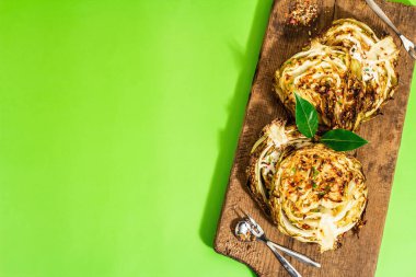 Bitki ve baharatlı ev yapımı vejetaryen biftekleri. Tahta kesme tahtasının üzerinde sağlıklı yiyecekler yemeye hazır. Modern sert ışık, koyu gölge, parlak yeşil arkaplan, üst manzara