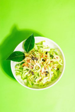 Bahar diyeti salatası. Taze vejetaryen vitamin yiyeceği. Dilimlenmiş lahana, baharat, zeytinyağı, kuru böğürtlen. Sağlıklı yaşam tarzı kavramı. Modaya uygun sert ışık, koyu gölge, parlak yeşil arkaplan, üst manzara