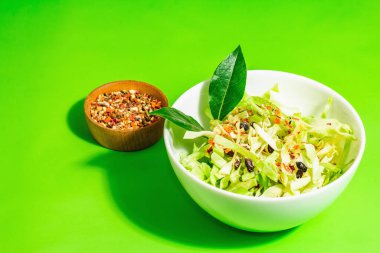 Bahar diyeti salatası. Taze vejetaryen vitamin yiyeceği. Dilimlenmiş lahana, baharat, zeytinyağı, kuru böğürtlen. Sağlıklı yaşam tarzı kavramı. Modaya uygun sert ışık, koyu gölge, parlak yeşil arkaplan, kapat