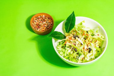 Bahar diyeti salatası. Taze vejetaryen vitamin yiyeceği. Dilimlenmiş lahana, baharat, zeytinyağı, kuru böğürtlen. Sağlıklı yaşam tarzı kavramı. Modaya uygun sert ışık, koyu gölge, parlak yeşil arkaplan, kopyalama alanı