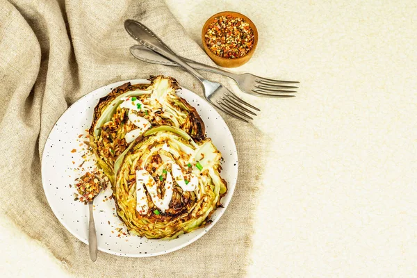 Ev yapımı vejetaryen lahana bifteği, baharat ve sos. Sağlıklı yiyecekler servis tabağında yemeye hazır, çatal bıçak takımı. Taş beton zemin, üst görünüm