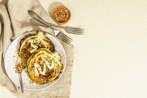 Ev yapımı vejetaryen lahana bifteği, baharat ve sos. Sağlıklı yiyecekler servis tabağında yemeye hazır, çatal bıçak takımı. Taş beton zemin, üst görünüm