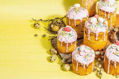 Geleneksel Paskalya pastası. Şekerleme ve dekorlu şenlikli tatlı yiyecekler. Yumurta, yuva, söğüt, modaya uygun sert ışık, karanlık gölge. Parlak sarı arkaplanda geleneksel pişirme, alanı kopyala