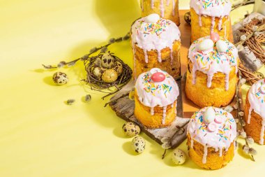 Geleneksel Paskalya pastası. Şekerleme ve dekorlu şenlikli tatlı yiyecekler. Yumurta, yuva, söğüt, modaya uygun sert ışık, karanlık gölge. Parlak sarı arkaplanda geleneksel pişirme, alanı kopyala