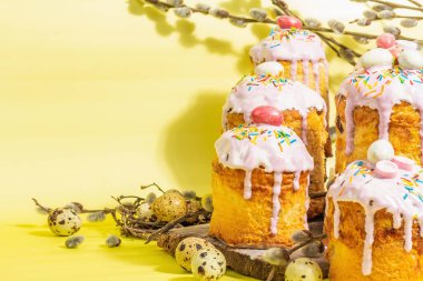 Geleneksel Paskalya pastası. Şekerleme ve dekorlu şenlikli tatlı yiyecekler. Yumurta, yuva, söğüt, modaya uygun sert ışık, karanlık gölge. Parlak sarı arkaplanda geleneksel pişirme, alanı kopyala