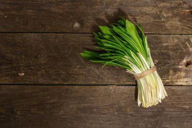 Taze bahar hasadı Ramson veya yaban pırasası. Eski ahşap masa zemininde mis kokulu yapraklar, sert ışık, koyu gölge, üst manzara