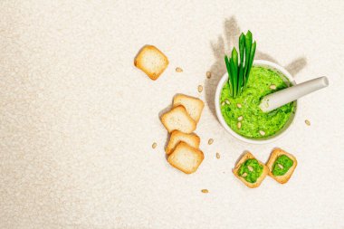 Kızarmış ekmeğe zeytinyağı sürülmüş Ramson pesto. Taze pırasa yaprakları ve çam fıstığı. Baharatlı aperatif ya da yemek pişirmek için malzeme. Sert ışık, koyu gölge, taş zemin, üst görünüm