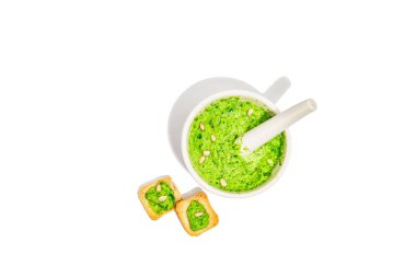 Beyaz arka planda zeytinyağı, parmesan ve çam fıstıklı Ramson pesto. Bir kase parfüm, baharatlı aperatif ya da yemek pişirmek için malzeme. Sert bir ışık, karanlık bir gölge, üst manzara.