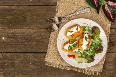 Pişmiş akordeon patatesler taze yeşillikler, mayalanmış sebzeler ve bezelye filizi. Geleneksel Amerikan yemekleri, ev yapımı vegan diyeti. Ahşap arkaplan, rustik biçim, pankart biçimi