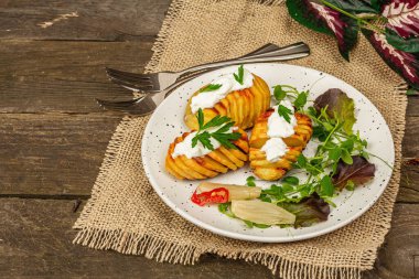 Pişmiş akordeon patatesler taze yeşillikler, mayalanmış sebzeler ve bezelye filizi. Geleneksel Amerikan yemekleri, ev yapımı vegan diyeti. Ahşap arkaplan, rustik biçim, kopyalama alanı