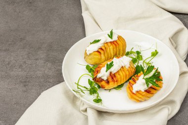 Taze bezelye filizli fırında akordeon patatesleri. Geleneksel Amerikan yemekleri, ev yapımı vegan diyeti. Taş beton zemin, düz yatış, kopyalama alanı