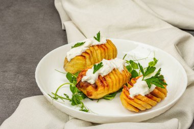 Taze bezelye filizli fırında akordeon patatesleri. Geleneksel Amerikan yemekleri, ev yapımı vegan diyeti. Taş beton zemin, düz zemin, yakın plan