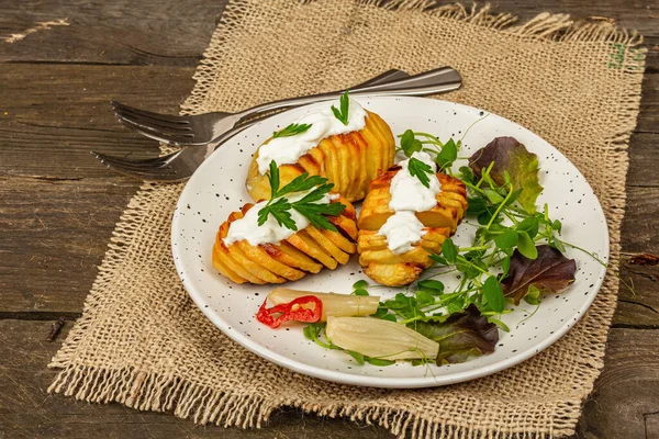 Pişmiş akordeon patatesler taze yeşillikler, mayalanmış sebzeler ve bezelye filizi. Geleneksel Amerikan yemekleri, ev yapımı vegan diyeti. Ahşap arkaplan, rustik biçim, kopyalama alanı