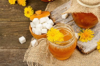 Karahindiba reçeli ya da cam kavanozda bir buket taze karahindiba çiçeğiyle bal. Mevsimlik ürün, köy tarzı, ahşap arka plan, yakın plan.