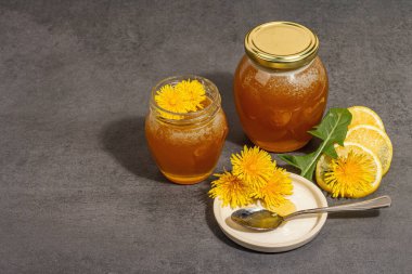 Karahindiba reçeli ya da cam kavanozda taze karahindiba çiçekleri olan bal. Mevsimlik ürün, modaya uygun sert ışık, karanlık gölge. Taş beton arkaplan, kopyalama alanı