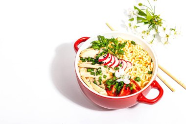 Tavuk, sebze ve otlu Asya erişteleri beyaz arka planda izole edilir. Geleneksel Japon çorbası, çorba ve kiraz çiçekleri.