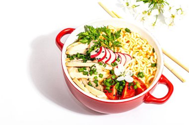 Tavuk, sebze ve otlu Asya erişteleri beyaz arka planda izole edilir. Geleneksel Japon çorbası, çorba ve kiraz çiçekleri.