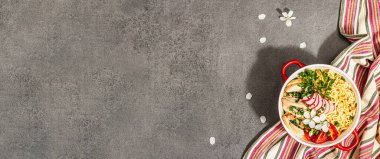 Kırmızı bir kasede tavuk, sebze ve otlu Asya eriştesi. Geleneksel Japon çorbası, çorba ve kiraz çiçekleri. Taş beton zemin, modaya uygun sert ışık, koyu gölge, afiş biçimi