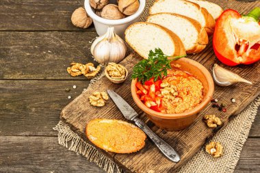 Geleneksel Ortadoğu sosu Muhammara. Ceviz ve baharatlı kavrulmuş kırmızı dolma biber. Seramik bir kasede düz ekmekle servis edilir, eski ahşap arka plan, kopyalama alanı