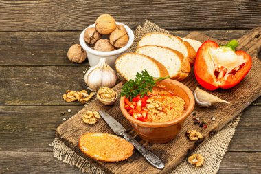 Traditional Middle Eastern dip Muhammara. Roasted red bell pepper with walnuts and spices. Spread served with flatbread in a ceramic bowl, old wooden background, copy space