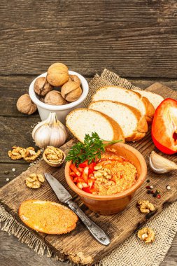 Geleneksel Ortadoğu sosu Muhammara. Ceviz ve baharatlı kavrulmuş kırmızı dolma biber. Seramik bir kasede düz ekmekle servis edilir, eski ahşap arka plan, kapat.