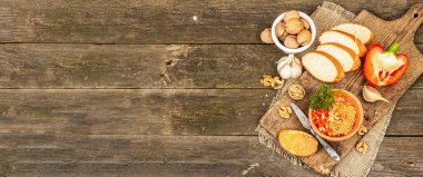 Geleneksel Ortadoğu sosu Muhammara. Ceviz ve baharatlı kavrulmuş kırmızı dolma biber. Seramik bir kasede düz ekmekle servis edilir, eski ahşap zemin, pankart biçimi