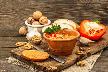 Geleneksel Ortadoğu sosu Muhammara. Ceviz ve baharatlı kavrulmuş kırmızı dolma biber. Seramik bir kasede düz ekmekle servis edilir, eski ahşap arka plan, kapat.