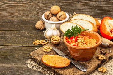 Geleneksel Ortadoğu sosu Muhammara. Ceviz ve baharatlı kavrulmuş kırmızı dolma biber. Seramik bir kasede düz ekmekle servis edilir, eski ahşap arka plan, kopyalama alanı