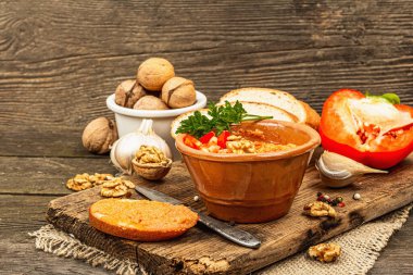 Geleneksel Ortadoğu sosu Muhammara. Ceviz ve baharatlı kavrulmuş kırmızı dolma biber. Seramik bir kasede düz ekmekle servis edilir, eski ahşap arka plan, kopyalama alanı