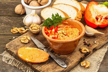 Traditional Middle Eastern dip Muhammara. Roasted red bell pepper with walnuts and spices. Spread served with flatbread in a ceramic bowl, old wooden background, close up