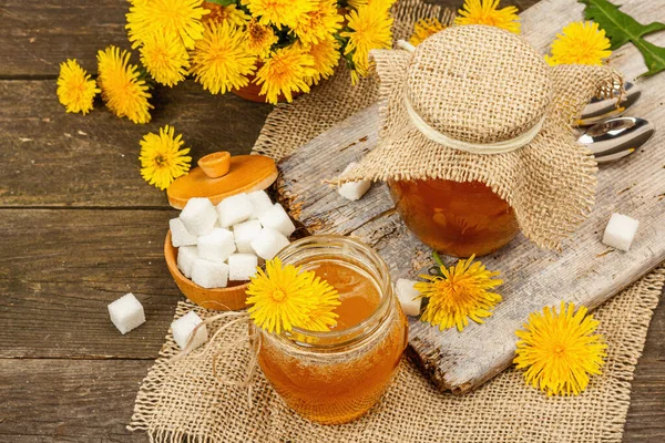 Karahindiba reçeli ya da cam kavanozda bir buket taze karahindiba çiçeğiyle bal. Mevsimlik ürün, köy tarzı, ahşap arka plan, yakın plan.