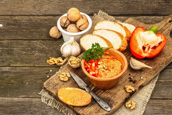 Geleneksel Ortadoğu sosu Muhammara. Ceviz ve baharatlı kavrulmuş kırmızı dolma biber. Seramik bir kasede düz ekmekle servis edilir, eski ahşap arka plan, kopyalama alanı