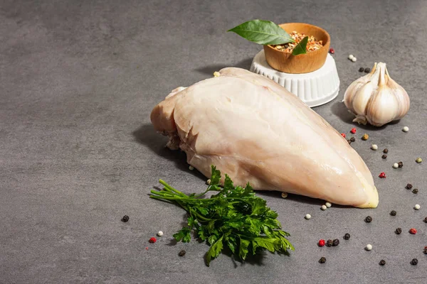 Raw chicken breast with spices and fresh parsley. Farm product, BIO poultry. Healthy food concept, trendy hard light, dark shadow. Grey concrete stone background, copy space