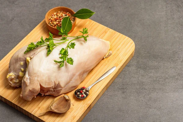 Raw chicken breast with spices and fresh parsley. Farm product, BIO poultry. Healthy food concept, trendy hard light, dark shadow. Grey concrete stone background, copy space
