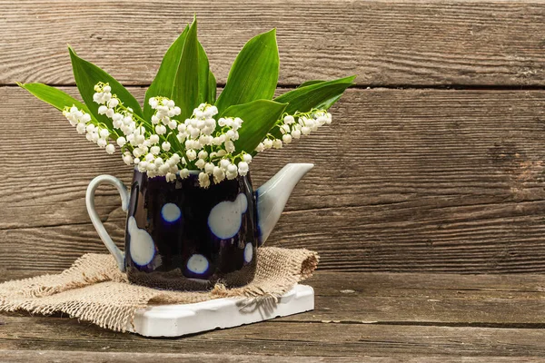 Yeşil yapraklı Lily Valley çiçek buketi. Anneler Günü ya da başka bir bayram için kutlama kartları tasarlamak için doğa objesi. Ahşap arka plan, kırsal tarz, sert ışık, karanlık gölge