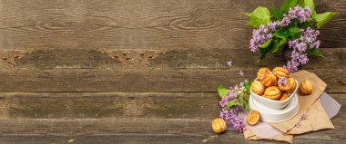 Yoğunlaştırılmış süt kremalı ceviz şeklinde kurabiyeler. Lezzetli kısa ekmekli sandviçler, kırsal tarzda modern vejetaryen pişirme. Eski ahşap arkaplan, pankart biçimi