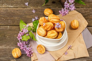 Yoğunlaştırılmış süt kremalı ceviz şeklinde kurabiyeler. Lezzetli kısa ekmekli sandviçler, kırsal tarzda modern vejetaryen pişirme. Eski tahta arkaplan, kopyalama alanı