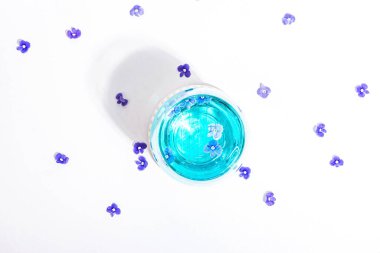 Soğuk tonik ve mavi beni unutsun. Beyaz arka planda tek başına duran çiçekler değil. İlkbahar konsepti, çiçekli element, sert ışık, koyu gölge, seçici odak, üst görünüm