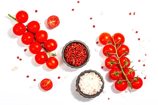 Cooking background with tomato cherry, sea salt, and rose peppercorn isolated on white background. A culinary concept with ripe vegetables and spices, top view