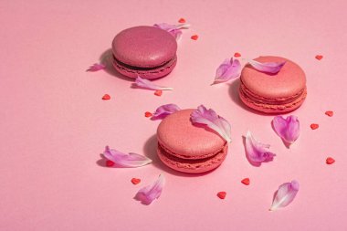 Pembe arka planda şakayık çiçekli makarna. Tatlı tatlı, renkli ve pastel renkli şeker renkleri, yaz konsepti. Romantik tarz, festival kartı, kopyalama alanı