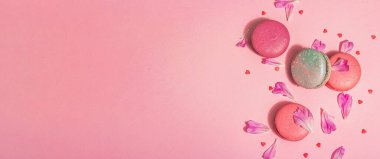 Pembe arka planda şakayık çiçekli makarna. Tatlı tatlı, renkli ve pastel renkli şeker renkleri, yaz konsepti. Romantik tarz, festival kartı, afiş biçimi