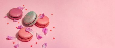 Pembe arka planda şakayık çiçekli makarna. Tatlı tatlı, renkli ve pastel renkli şeker renkleri, yaz konsepti. Romantik tarz, festival kartı, afiş biçimi