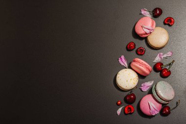 Şakayık çiçekli makarna ve siyah taştan bir arka planda olgun kirazlar. Tatlı tatlı, romantik stil, şenlik kartı, düz yatış, sert ışık, koyu gölge, üst manzara