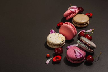 Şakayık çiçekli makarna ve siyah taştan bir arka planda olgun kirazlar. Tatlı tatlı, romantik stil, festival kartı, düz uzanma, sert ışık, karanlık gölge, kopyalama alanı