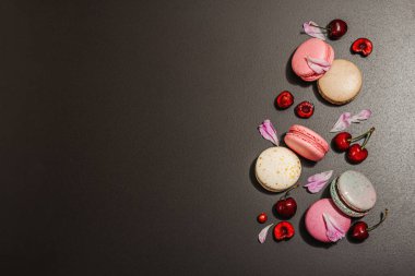 Şakayık çiçekli makarna ve siyah taştan bir arka planda olgun kirazlar. Tatlı tatlı, romantik stil, şenlik kartı, düz yatış, sert ışık, koyu gölge, üst manzara