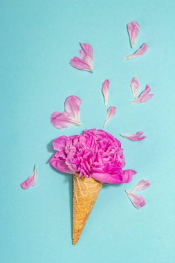 Mavi arka planda şakayıklı dondurma külahları. Çiçek yaprakları, yaz konsepti. Romantik tarz, şenlik kartı, sert ışık, koyu gölge, üst manzara