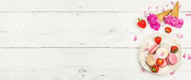 Beyaz ahşap arka planda çilek ve şakayık çiçekli makarna. Tatlı tatlı, romantik tarzı, düz yatış, sert ışık, koyu gölge, afiş biçimi