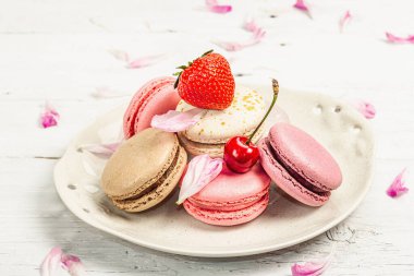 Beyaz ahşap bir arka planda çilekli, kirazlı ve şakayıklı çiçek yaprakları. Tatlı tatlı, romantik stil, düz yatış, sert ışık, karanlık gölge, yakın çekim