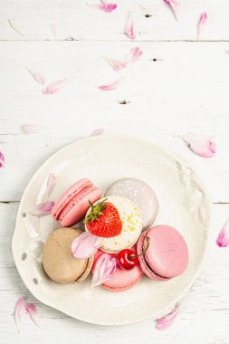 Beyaz ahşap bir arka planda çilekli, kirazlı ve şakayıklı çiçek yaprakları. Tatlı tatlı, romantik tarzı, düz yatış, sert ışık, koyu gölge, üst manzara